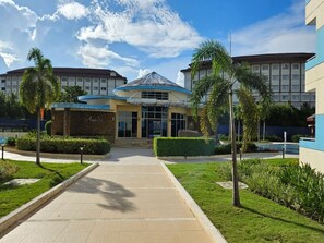 A hotel entrance with a covered walkway, palm trees, and a pool area. - Amisa Private Residences Tower C (Lapu-Lapu)