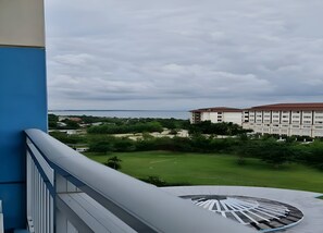 A view from a balcony overlooking a grassy area with a building in the background. - Amisa Private Residences Tower C (Lapu-Lapu)
