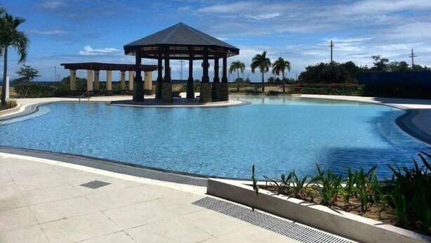 Ein Pool mit einer Laube, Palmen und blauem Himmel.