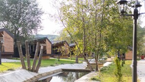 A serene outdoor area with a small water feature, wooden buildings, and a lamp post.