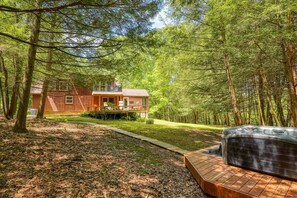 A cabin with a deck, surrounded by dense forest.