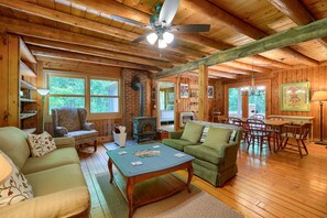Un interior de cabaña acogedor, con chimenea, muebles de madera y ventanas amplias.