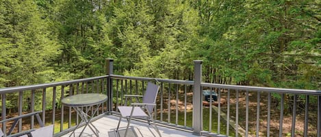 Um terraço com mesa e cadeiras, com vista para uma área arborizada.
