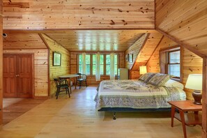 Een slaapkamer in een houten hutje, met een bed, een bureau en een stoel.
