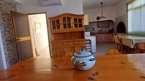 Un coin repas avec une table en bois, un bol décoratif et une cuisine en arrière-plan.