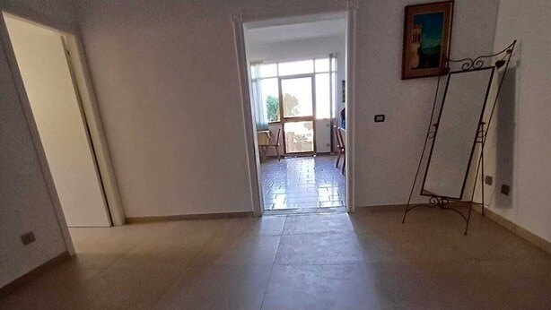 Une pièce spacieuse dotée d’une grande fenêtre, d’une porte donnant sur un espace extérieur et d’un présentoir en métal avec un miroir.
