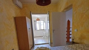 Une chambre à coucher avec une couvre-lit à motifs, une armoire en bois et une porte donnant sur un balcon.