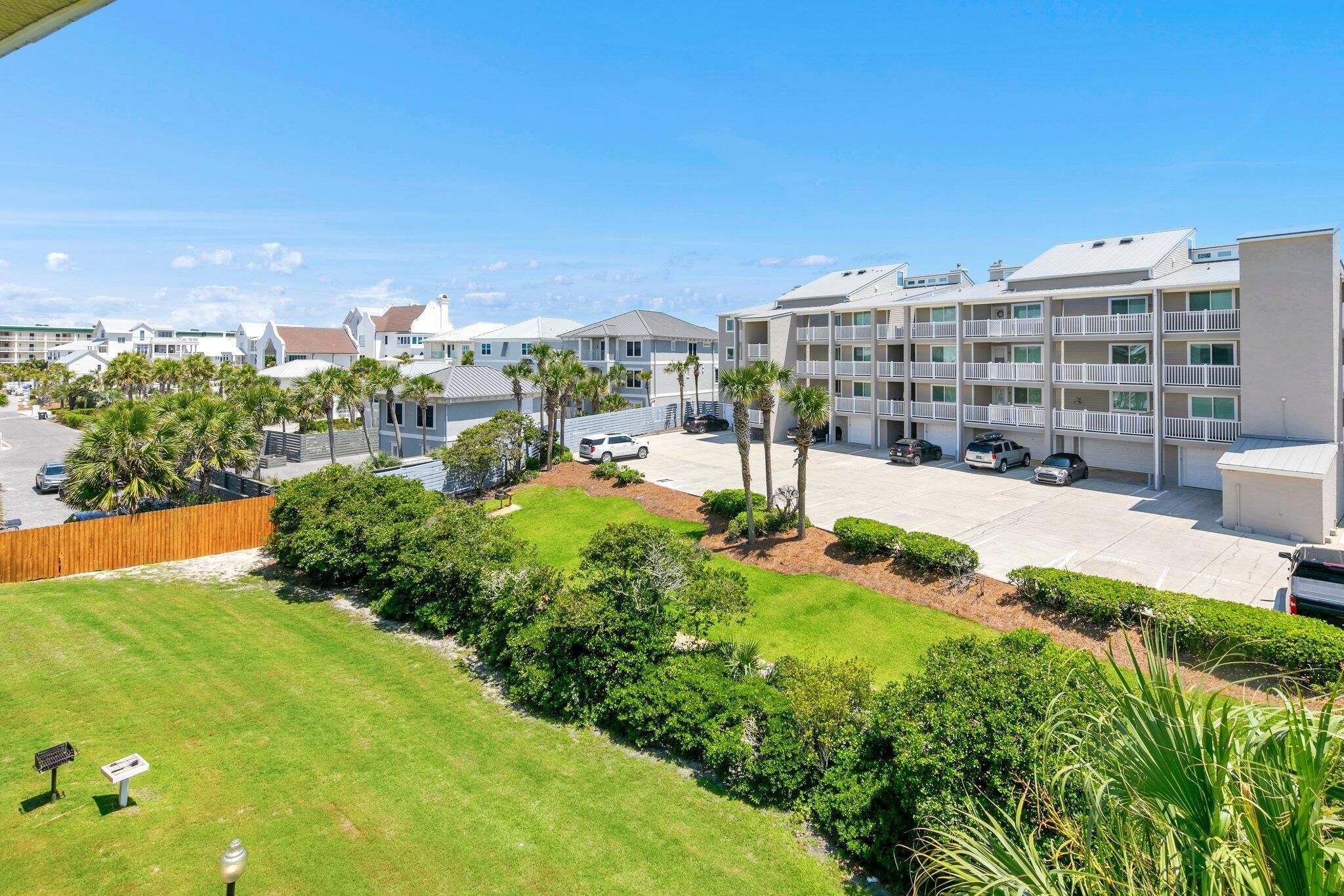 A multi-story hotel with a parking lot, surrounded by palm trees and well-maintained lawns.