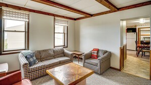 A room with two checkered sofas, a wooden coffee table, and a small table. There is a doorway leading to a kitchen area. - Manitowoc Lakefront Home on 15 Acres: Dogs OK! (Manitowoc)