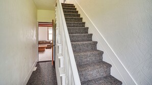 A carpeted staircase with white railings leading to a room with a checkered sofa and a wooden coffee table. - Manitowoc Lakefront Home on 15 Acres: Dogs OK! (Manitowoc)