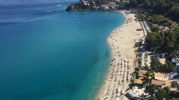 An aerial view of a beach with a long stretch of beach, numerous umbrellas, and people. - Maison Stalettì between sky, sea and prickly pears (Lucerta)