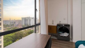 Een modern appartement met een groot raam, een wasmachine en uitzicht op de stad.