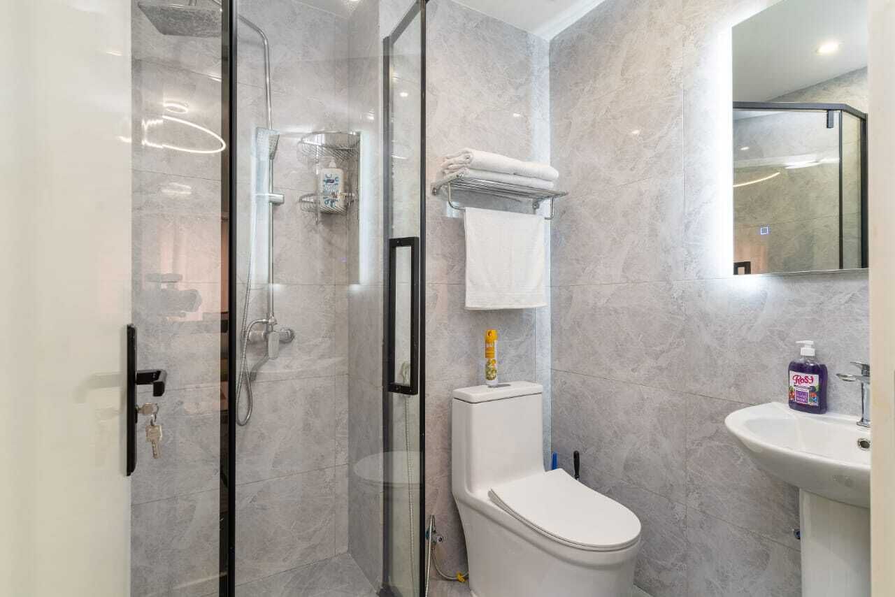 A modern bathroom with a glass-enclosed shower, a toilet, and a sink.