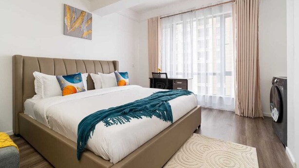 Een moderne slaapkamer met een groot bed, een bureau en een wasmachine.