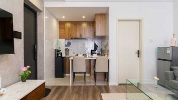A modern kitchen with wooden cabinets, a dining area with two chairs, and a glass coffee table.