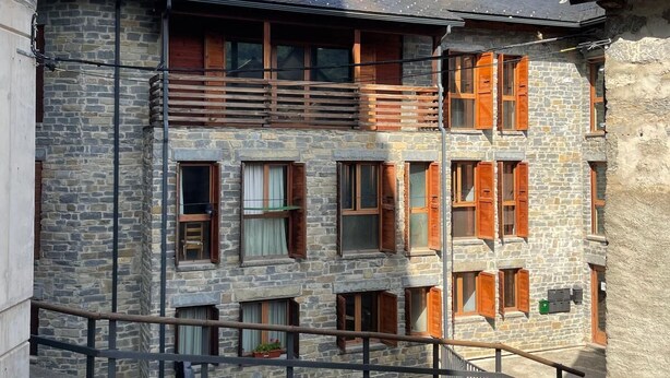 A stone building with multiple windows and balconies, set against a mountainous backdrop. - Snö Apartamentos Escarrilla (Sallent de Gallego)