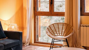 A cozy room with a sofa, a wicker chair, and a small table. - Snö Apartamentos Escarrilla (Sallent de Gallego)