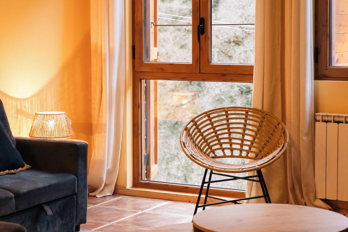 A cozy room with a sofa, a wicker chair, and a small table.
