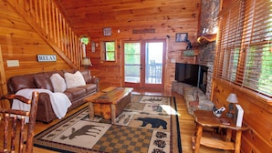 L’intérieur chaleureux d’un chalet avec un canapé en cuir marron, une table basse en bois et une cheminée.