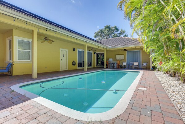A swimming pool with a tiled deck, a covered patio area, and a small seating area with chairs. - 5 Mi to Jupiter Beach Park: Poolside Oasis! (Jupiter)