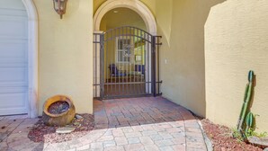 A gated entrance with a metal gate, a potted plant, and a cactus. - 5 Mi to Jupiter Beach Park: Poolside Oasis! (Jupiter)