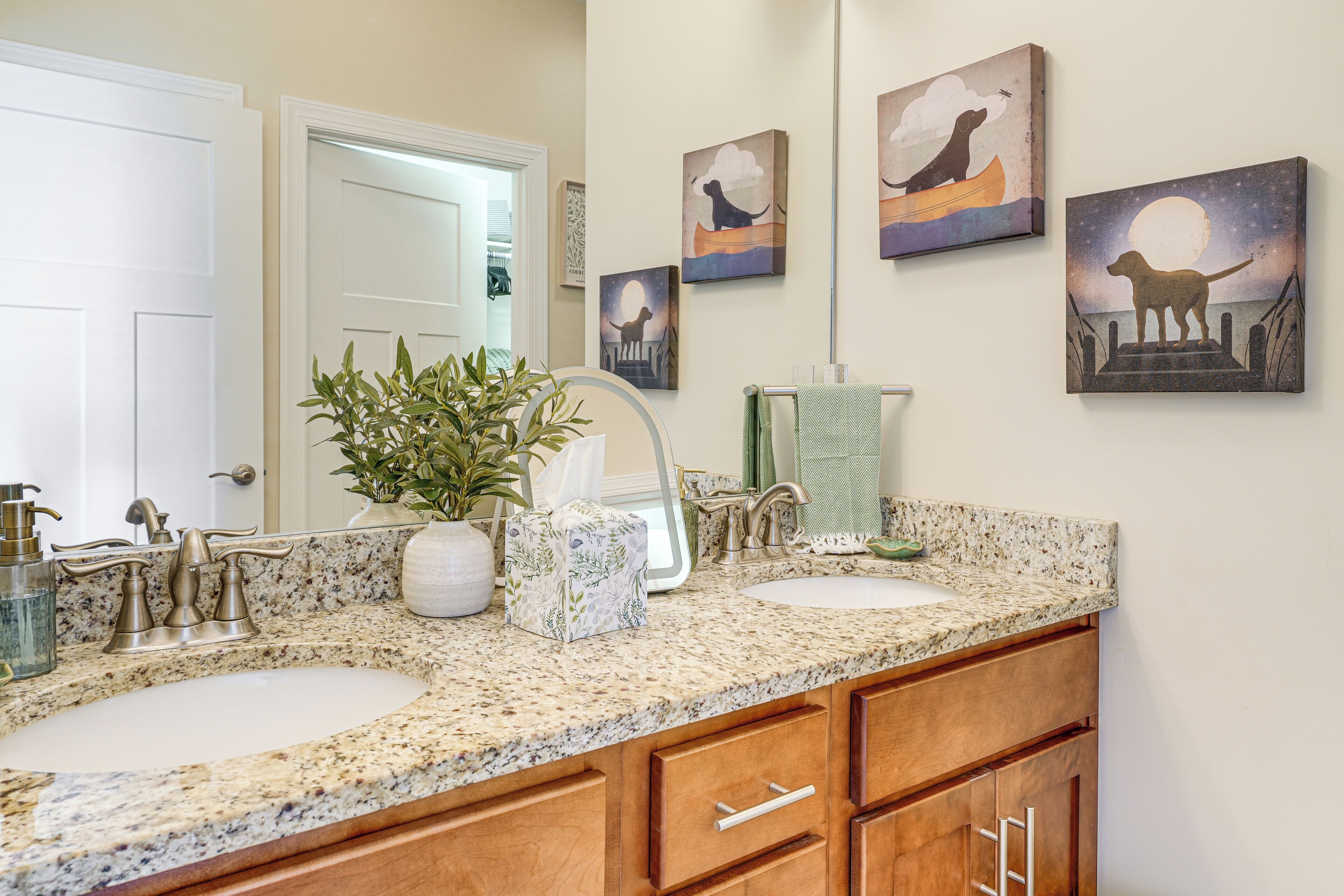 A bathroom with two sinks, a mirror, and artwork on the wall.