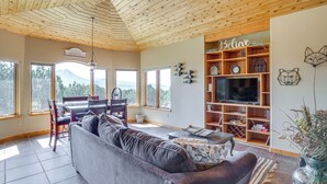 A cozy living room with a wooden ceiling, a sofa, a TV, and a bookshelf. - Hunt, Fish & Explore: Mtn-View Home in Hotchkiss (Hotchkiss)