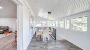 A spacious room with a dining area featuring a round table and chairs, large windows, and a view of greenery outside. - Waterfront Lake Eufaula Home: Dock & Beach Access! (Eufaula)