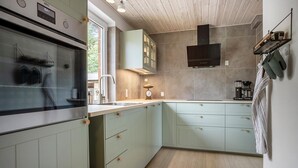 Una cocina moderna con armarios verde claro, un horno de acero inoxidable y una campana extractora integrada.