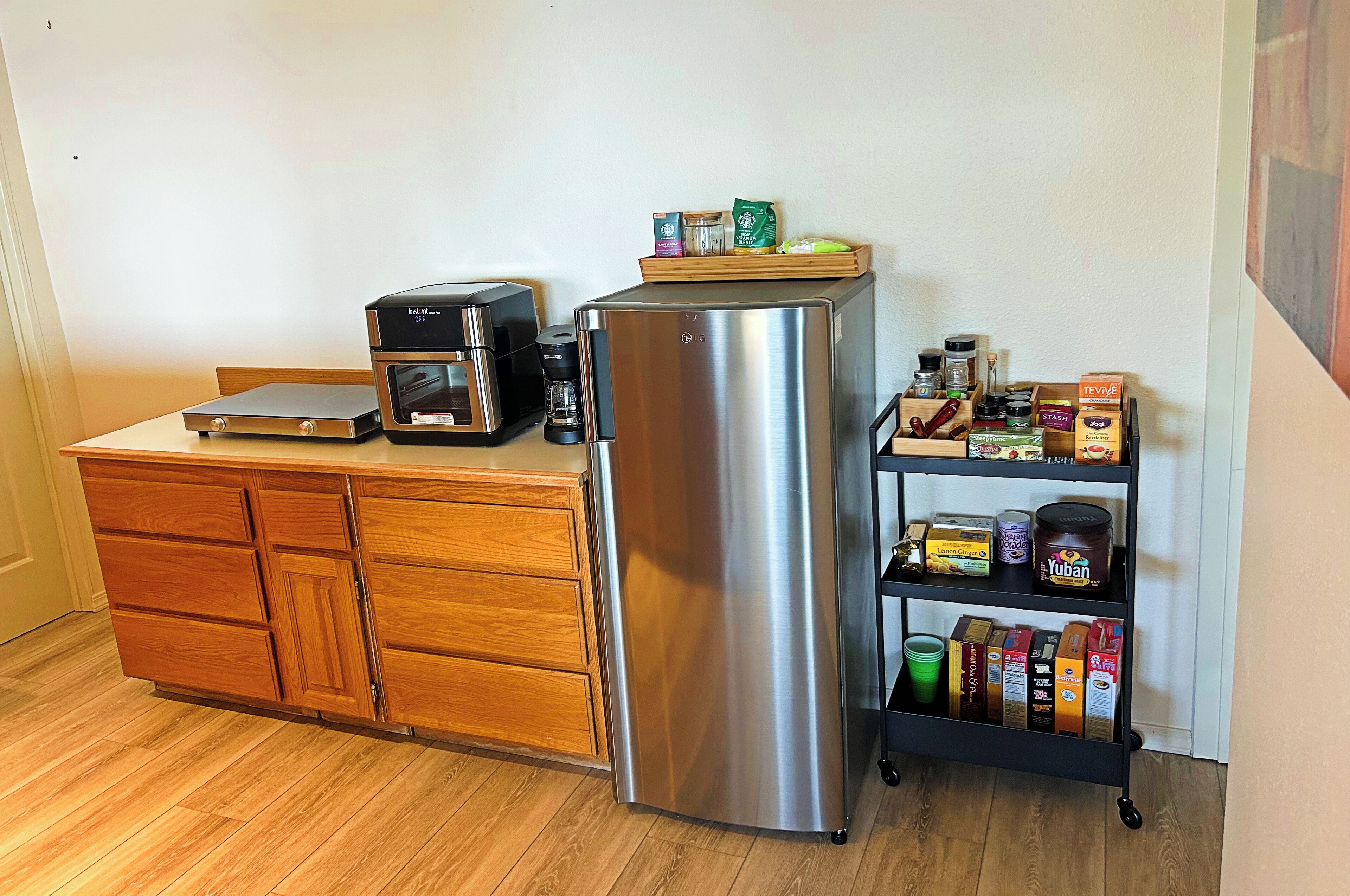 A kitchen with a stainless steel refrigerator, a coffee maker, and a wooden cabinet.