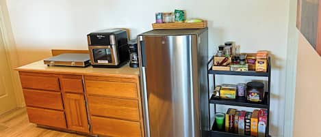 A kitchen with a stainless steel refrigerator, a coffee maker, and a wooden cabinet.