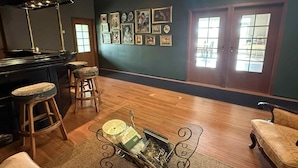 A cozy room with a piano, wooden stools, a glass table with magazines, and a large window with a view. - Freya Farm (Storinupur)