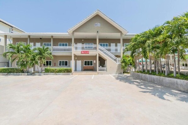A hotel with a central entrance, multiple balconies, and palm trees. - Highway Hotel (Hua Hin)