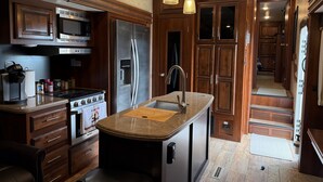 Een moderne keuken met houten kastjes, roestvrijstalen apparatuur en hanglampen.
