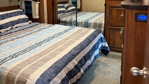Een slaapkamer met een groot bed, een houten garderobe en een badkamers deur.