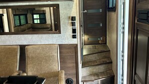A compact kitchen with built-in appliances, a seating area, and a staircase leading to a door. - Cozy 2-bedroom mobile home in front of lake pleasant. (Beaver)