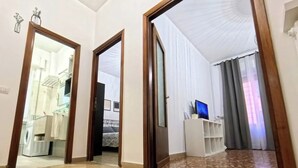 A spacious living area with a large mirror, a television, and a white shelving unit. - The little house in the hills - Appio/Tuscolano (Roma)