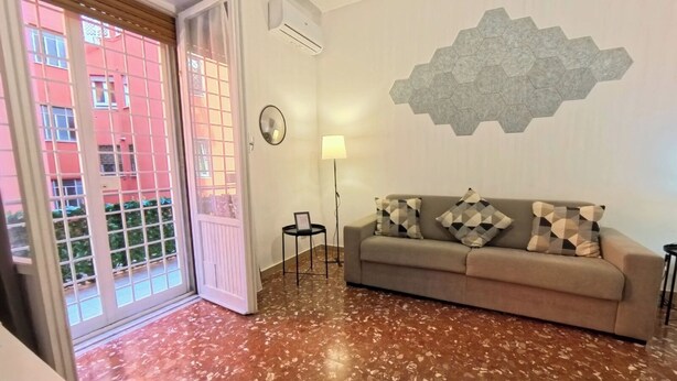 A living room with a sofa, a lamp, a wall clock, and a hexagonal wall decoration. - The little house in the hills - Appio/Tuscolano (Roma)