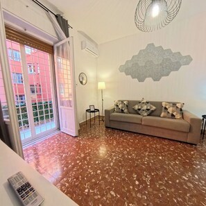Een woonkamer met een bank, een lamp, een wandklok en een zeshoekige decoratie aan de muur.