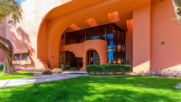 A modern building with a curved facade, large windows, and a well-maintained lawn. - CASA MARCO - Anasazi Village - Modern Condo (Phoenix)