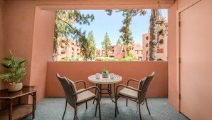 A balcony with two wicker chairs and a small table, overlooking a row of buildings with balconies. - CASA MARCO - Anasazi Village - Modern Condo (Phoenix)