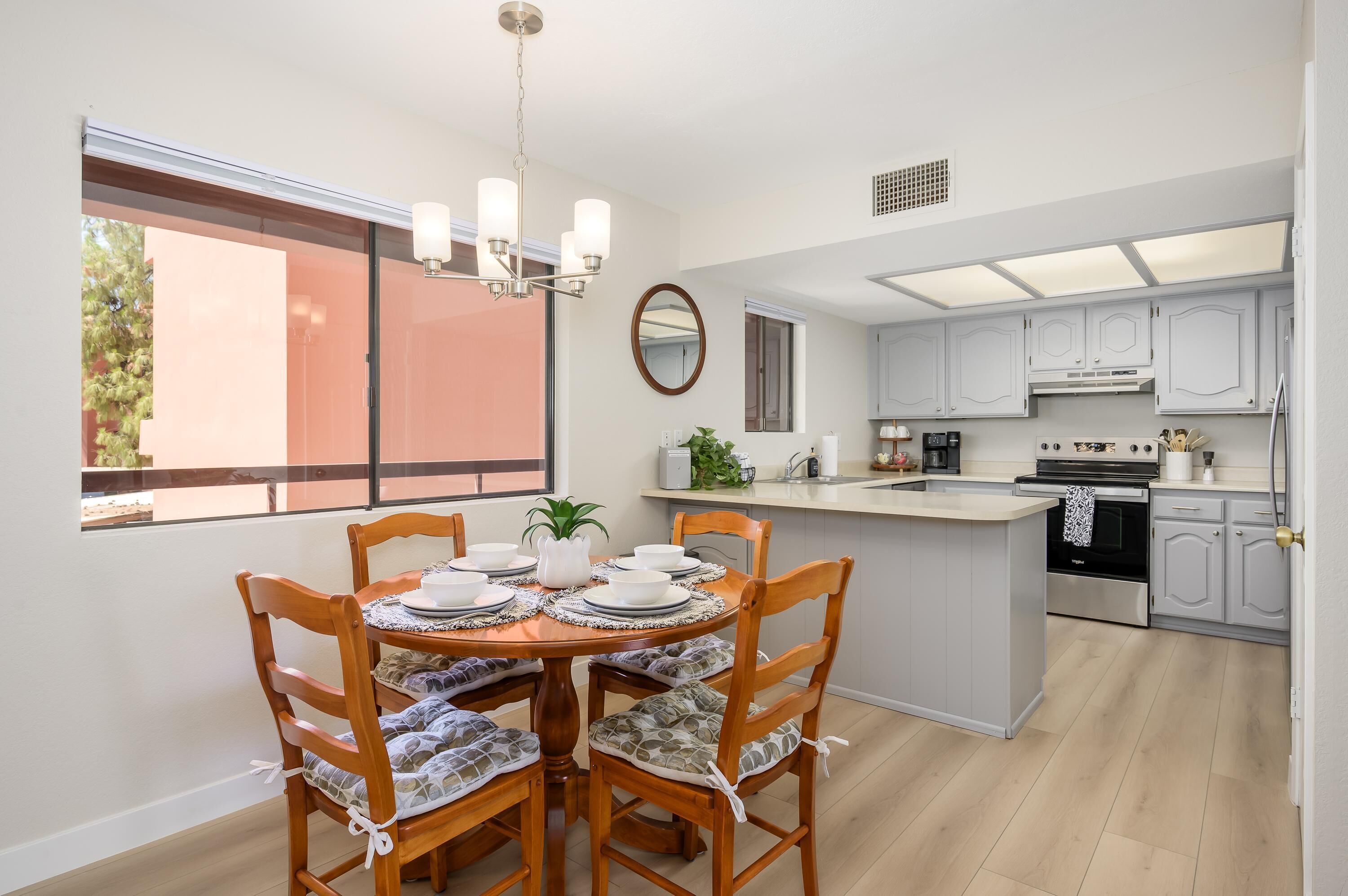 A modern kitchen with a central island, white cabinetry, and a dining area with a round table and chairs.
