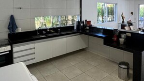 Una cocina moderna con armarios blancos, encimeras negras y piso de baldosas.