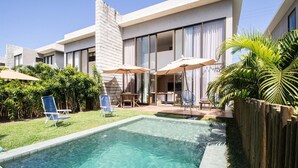Una casa moderna con piscina, area salotto esterna e verdeggiante vegetazione.