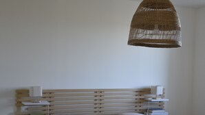 A bedroom with a wooden headboard, white bedding, a bedside table with a lamp, and a woven hanging light fixture. - Le Relais du Berger: House in the heart of the salt meadows (Céaux)