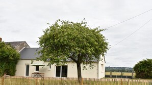 A house with a fenced yard, a tree, and a table with an umbrella. - Le Relais du Berger: House in the heart of the salt meadows (Céaux)