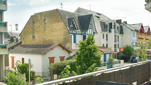 A balcony with a table and chairs, overlooking a row of colorful buildings and a clear sky.