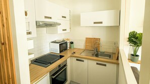 A compact kitchen with white cabinets, a microwave, a stove, and a sink.