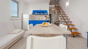 A modern kitchen with blue cabinets, a white refrigerator, and a wooden staircase.