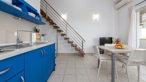 A modern kitchen with blue cabinets, a stainless steel sink, and a wooden staircase.